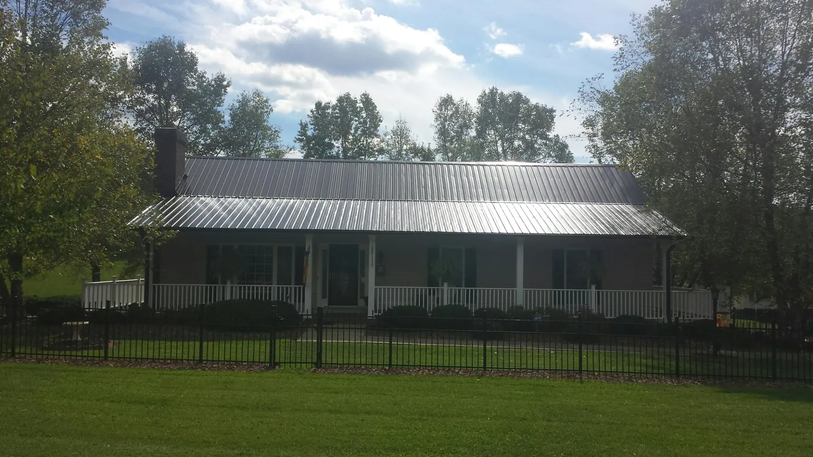 Gray metal roof on a brick ranch with a full width front porch — Gutter Guard Installation work by our crew in Harmony