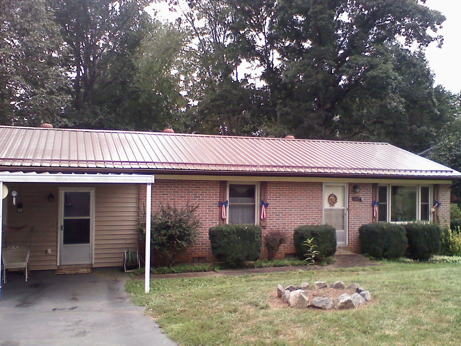 Bronze metal roof and carport on a brick ranch home — Roof Repair work by our crew in Harmony